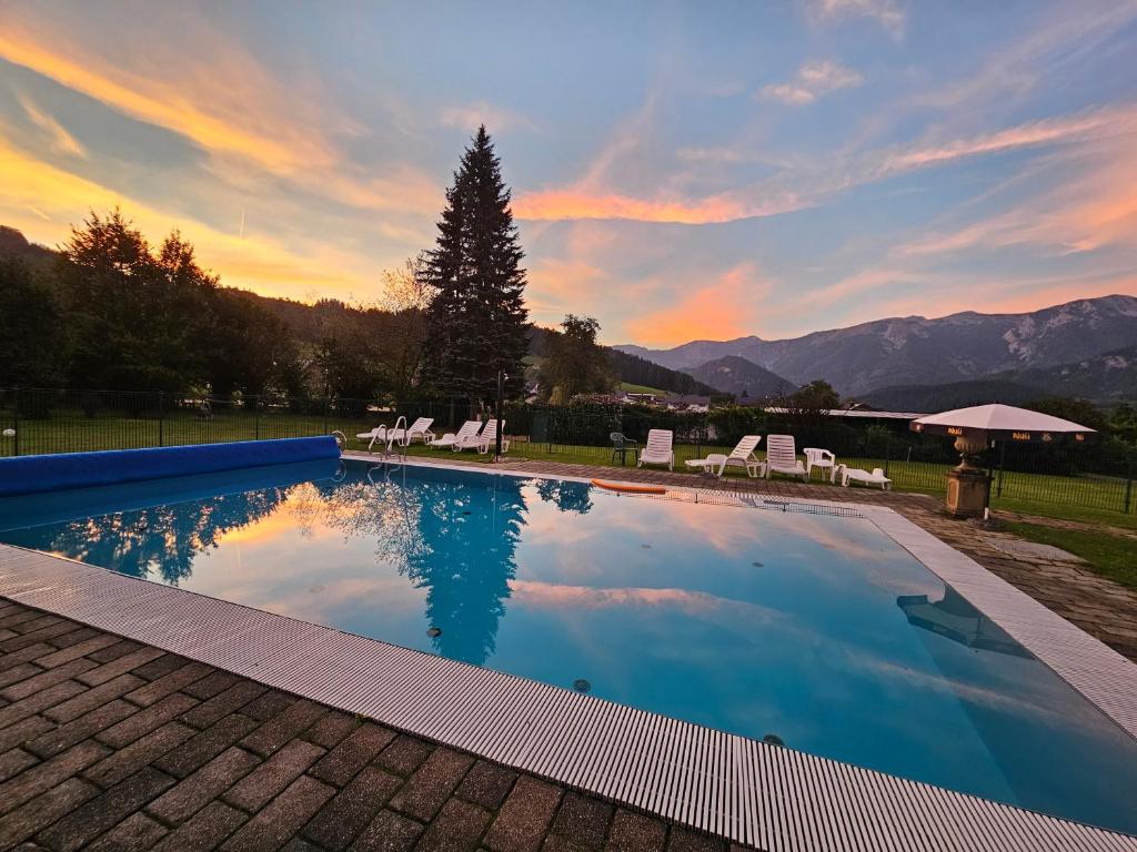 a swimming pool with a sunset in the background at Ferienwohnung Blick ins Grüne in Rossleithen