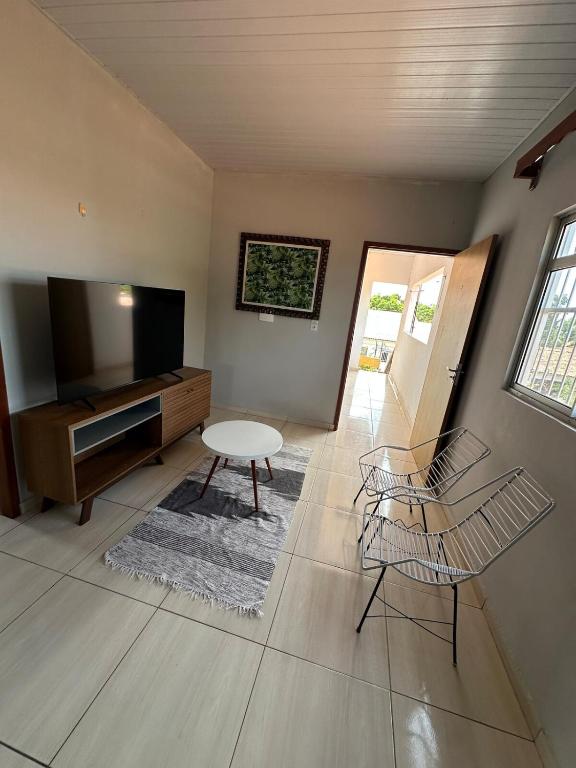 een woonkamer met een televisie en een tafel en stoelen bij Quarto privativo com sala e tv em Villa Hostel in Pedro II