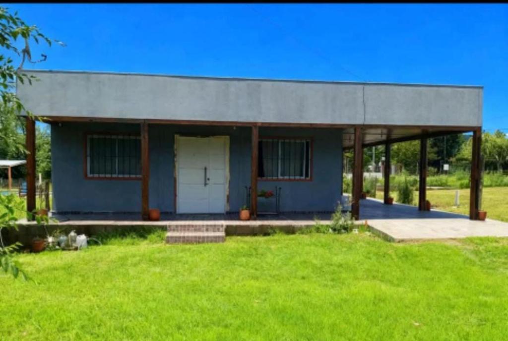 a small blue house with a grass yard at El Atardecer in Villa Giardino