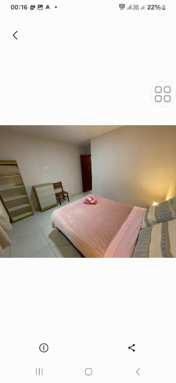 a bedroom with a large bed with a pink blanket at Quarto suite in Florianópolis