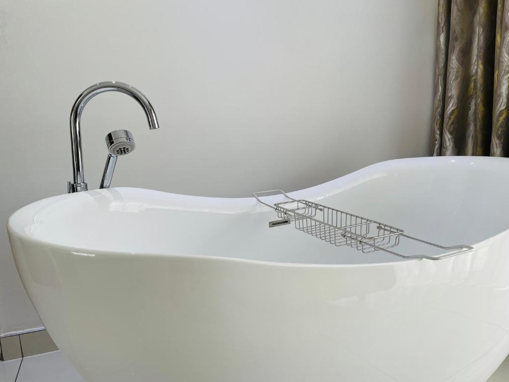 een bad met een wastafel en een kraan bij Loreho boutique in Mahikeng