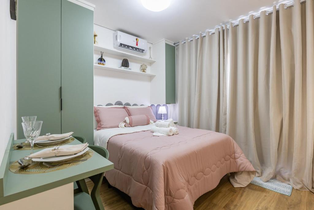 a bedroom with a pink bed and a table with plates at Apê novo, moderno, a 50 metros metrô República in São Paulo