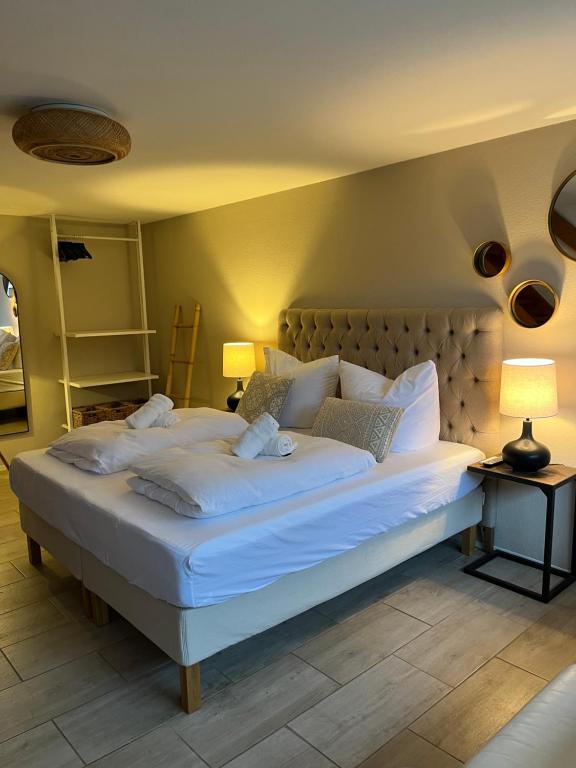een slaapkamer met een groot bed met witte lakens en kussens bij See-Maisonette mit Wellness-Sauna in Öhningen