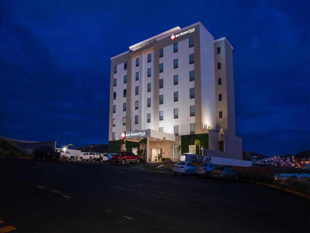 a hotel building with cars parked in a parking lot at Best Western Plus Chihuahua Juventud in Chihuahua