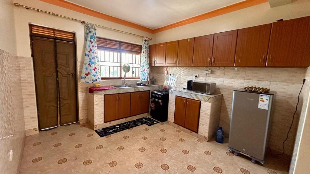 een keuken met houten kasten, een wastafel en een koelkast bij Pure Haven in Mbale