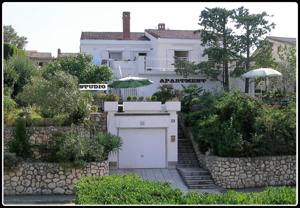 a white house with a garage in front of it at Casa 33 in Njivice