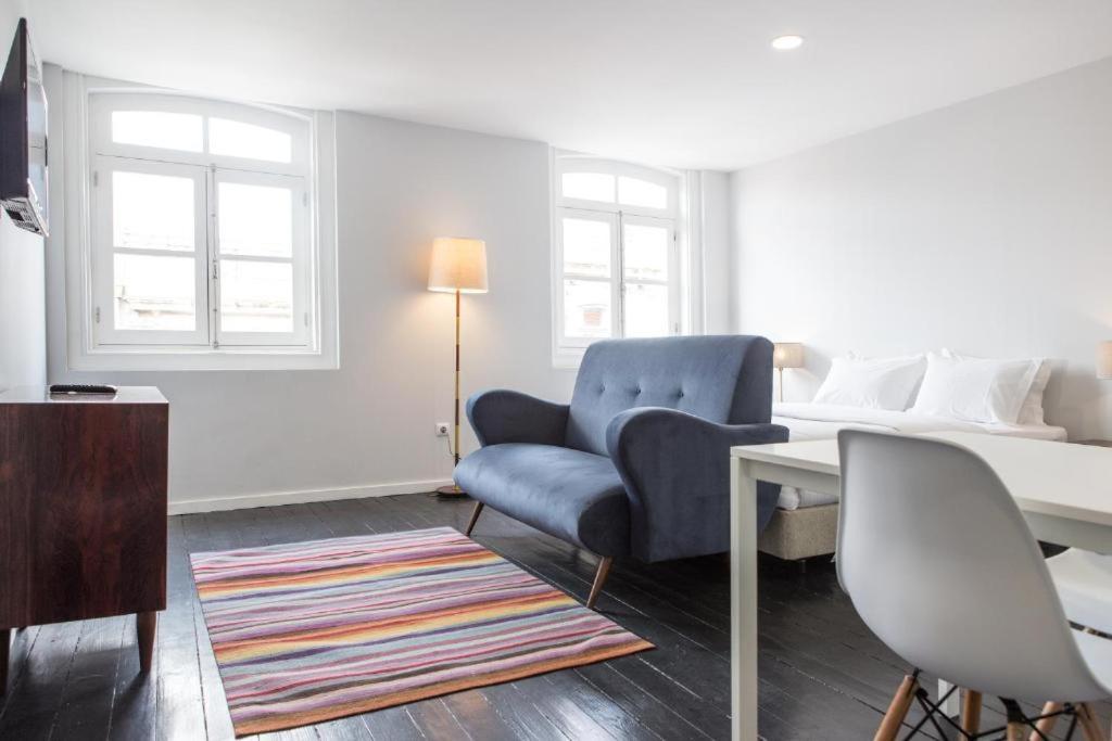 a living room with a bed and a blue chair at Porto República Suites in Porto