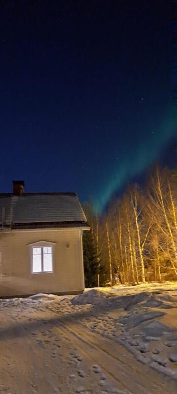 a house in the snow at night with the aurora at Spacious detached house for a larger group in Rovaniemi
