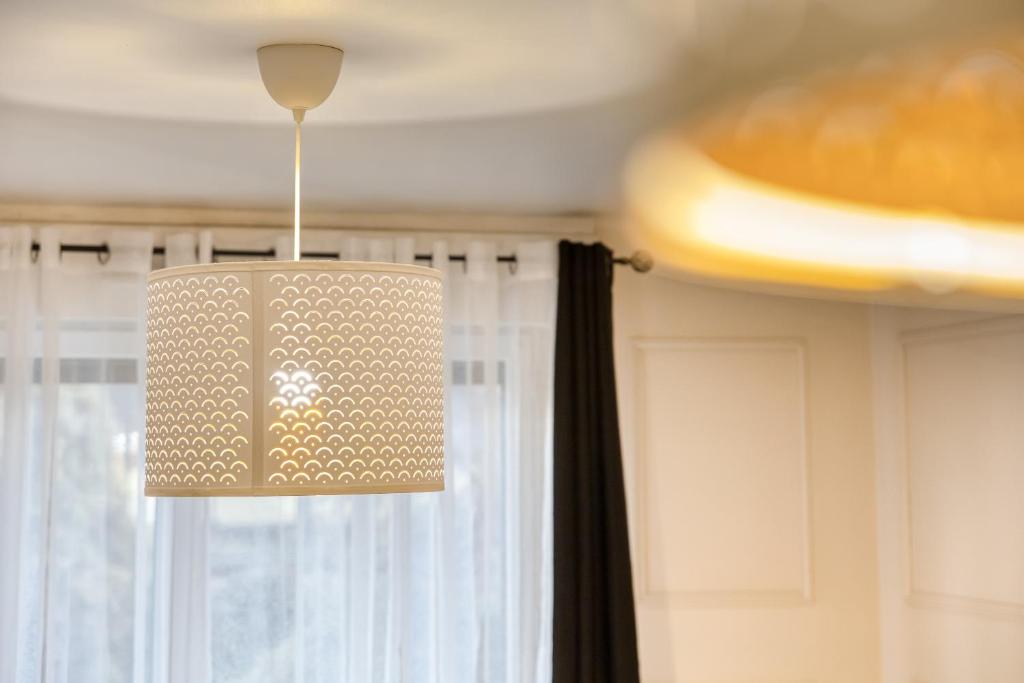 een hanglamp in een kamer met een raam bij Appartement 39m2 - Free Parking - Rer C - Métro 13-14 - Ascenseur - Easy Check in - in Asnières-sur-Seine