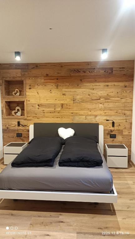 a large bed in a room with a wooden wall at Casa Zena in Tesero