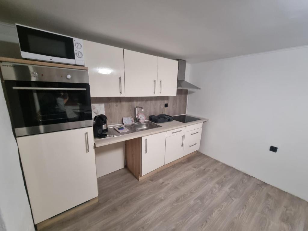 une cuisine avec des armoires blanches, un évier et un micro-ondes dans l'établissement Vienna Gateway - Self Check-In 24 - free parking, à Bockfließ