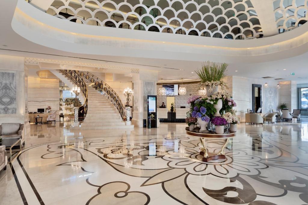 a lobby with a spiral staircase and flowers on the floor at CVK Park Bosphorus Hotel Istanbul in Istanbul