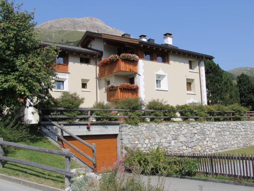 a house with a stone wall and a fence at Apartment Aivla by Interhome in Celerina