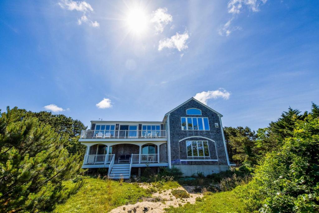 Una casa su una collina con il sole nel cielo di Stunning Water Views by Private Beach a Eastham