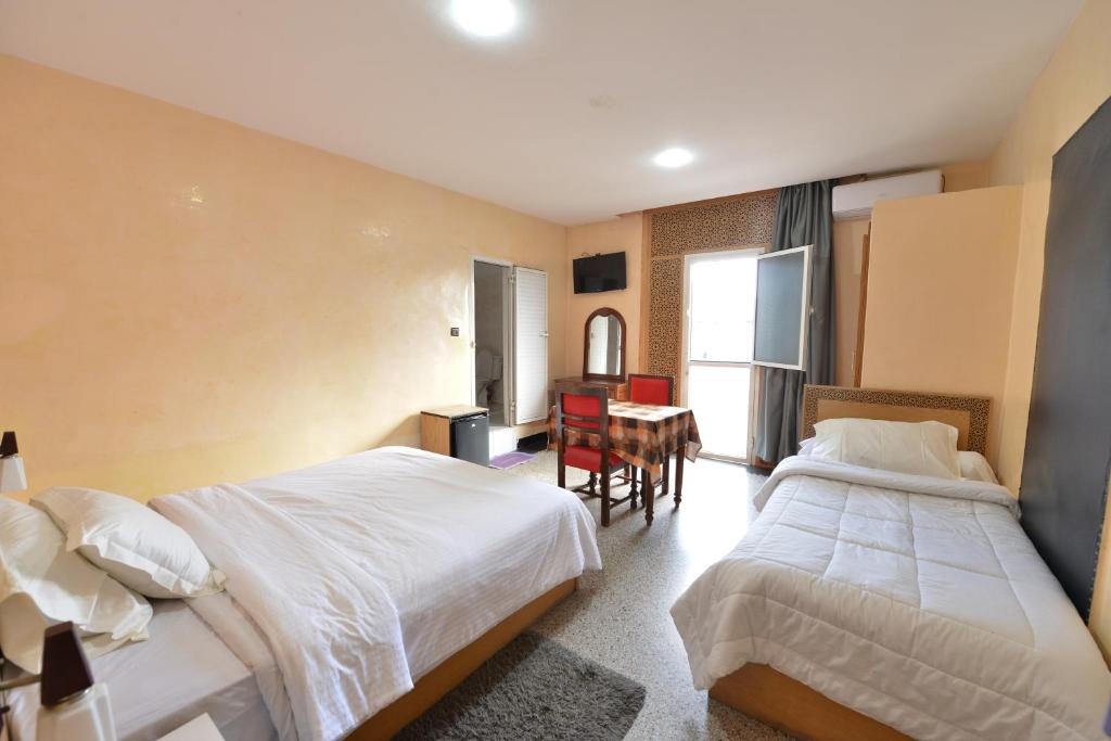 una habitación de hotel con dos camas y una mesa en HOTEL VELLEDA, en Rabat