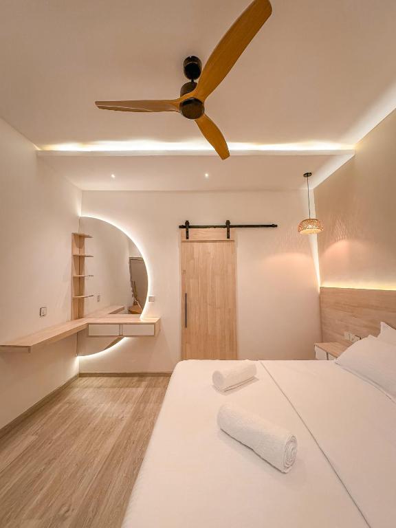 a bedroom with a ceiling fan and a bed at Cocomero Inn in Fulidhoo