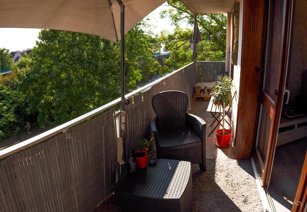 einen Balkon mit einem Stuhl und einem Sonnenschirm in der Unterkunft Au pied des quais avec balcon in Auxerre