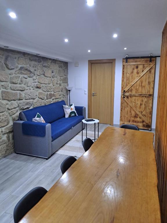 a living room with a blue couch and a wooden table at CriCastelo - Alojamento Local in Trancoso