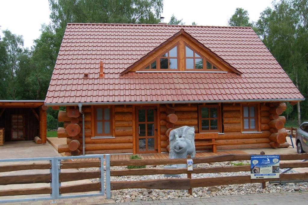 ein Blockhaus mit einer Bärenstatue davor in der Unterkunft Naturstamm Ferienhaus in Trassenheide