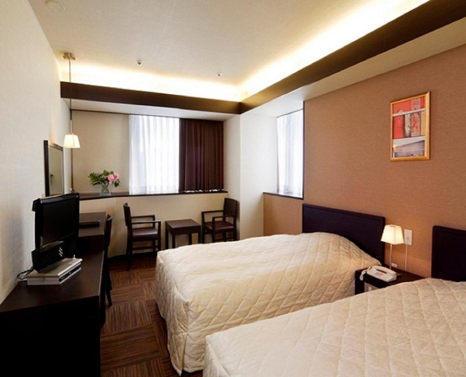a hotel room with two beds and a desk and a table at Niigata City Hotel in Niigata
