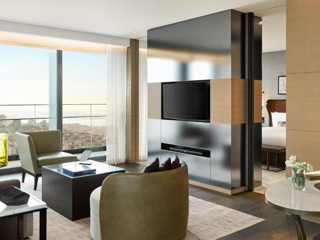 a living room with a television and a room with a bed at Fairmont Quasar Istanbul Hotel in Istanbul