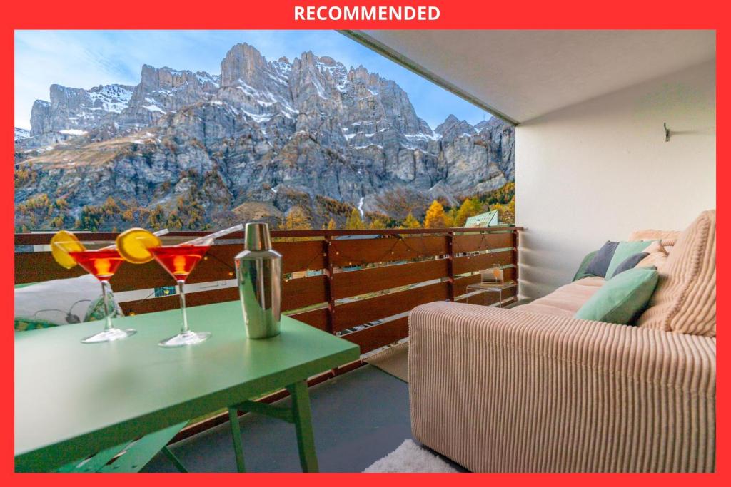 een balkon met een tafel en 2 wijnglazen bij Le Belvédère de Loèche in Leukerbad