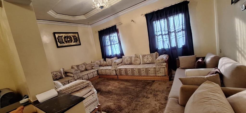a living room with couches and tables and windows at Appartement lumineux 2 pas à l'aéroport in Marrakech