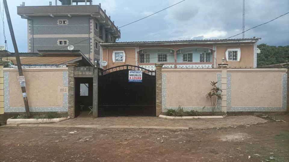 a building with a black door with a sign on it at Maison meublée VERTE in Yaoundé
