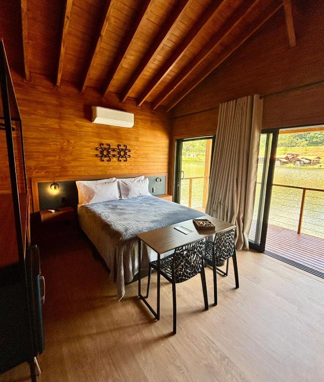 a bedroom with a bed and a table in it at Pousada reserva do J in Serra Negra