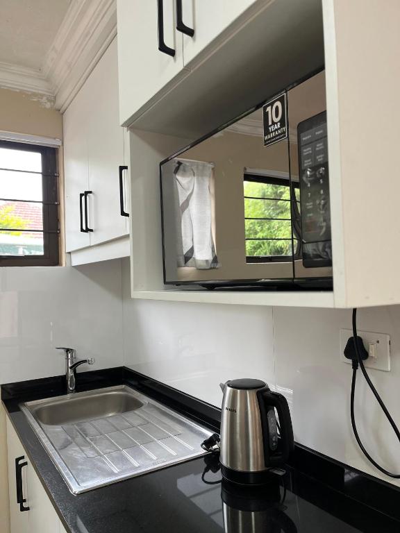 una cucina con lavello e microonde di Crème de la crème Tiny Cottage a Durban
