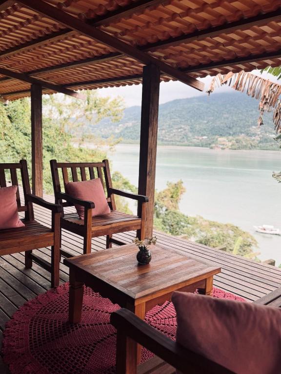 eine Veranda mit Stühlen und einem Tisch sowie Blick auf das Wasser in der Unterkunft Casa da Praia in Paraty