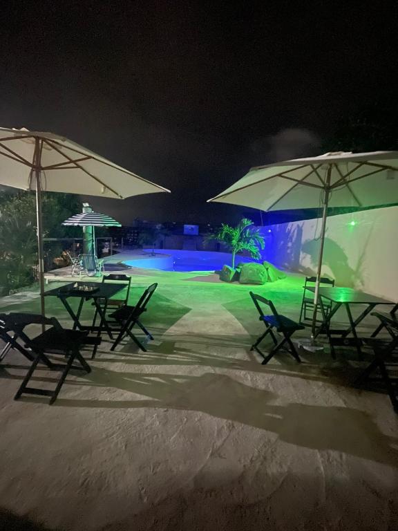 a group of tables and umbrellas on the beach at night at Caminho do mirante, suíte 5 in Iguaba Grande