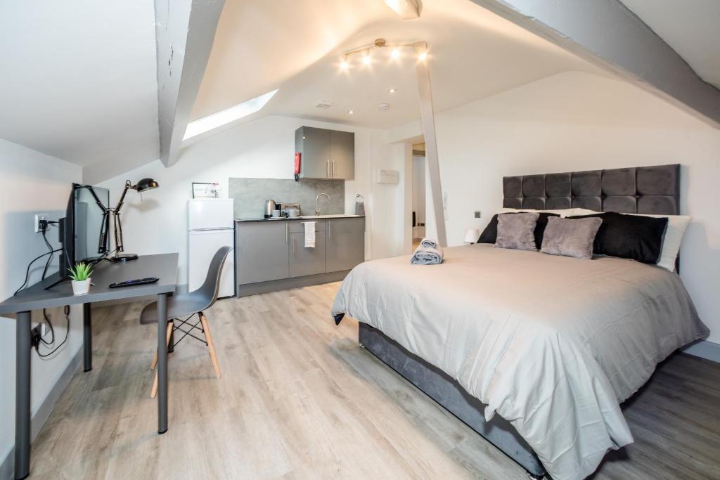 een slaapkamer met een bed, een bureau en een keuken bij Essential Studio in the Heart of Huddersfield in Huddersfield