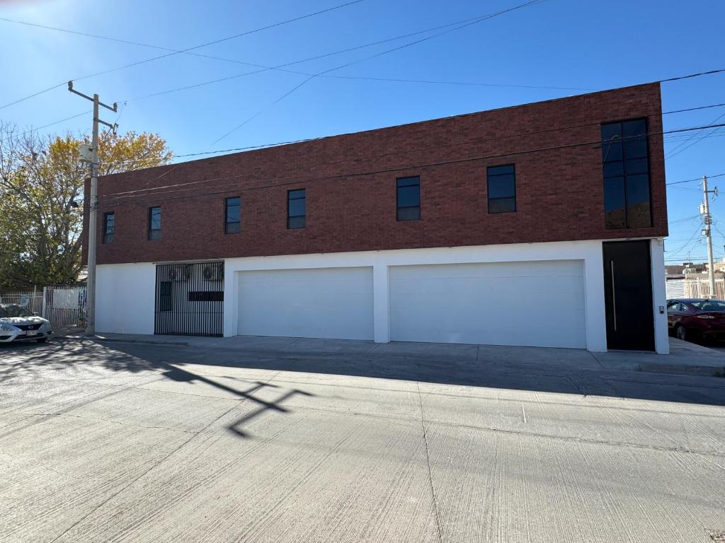 a brick building with two white garage doors at Lina Élite Suites in Chihuahua