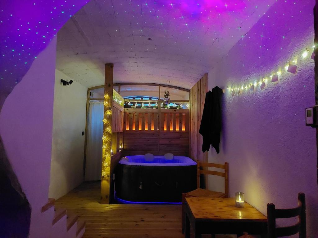 ein Zimmer mit einer Badewanne mit violetter Beleuchtung und einem Tisch in der Unterkunft JC's House of Happiness in Cabrières-dʼAigues