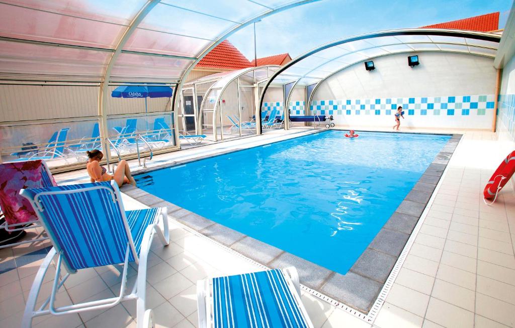 a swimming pool with chairs and people in it at Résidence Odalys Les Villas de la Baie in Le Crotoy