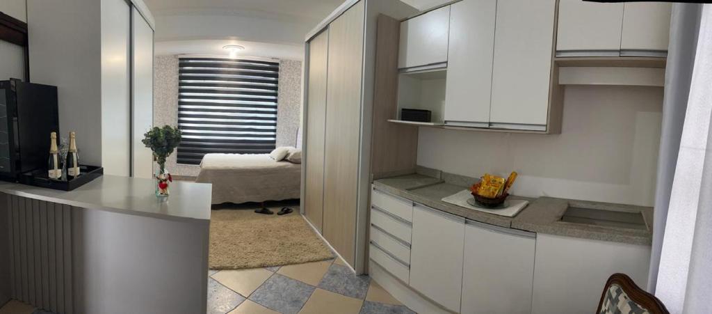 une cuisine avec des placards blancs et une chambre dans l'établissement Mirante LUZ FLORIPA, à Florianópolis