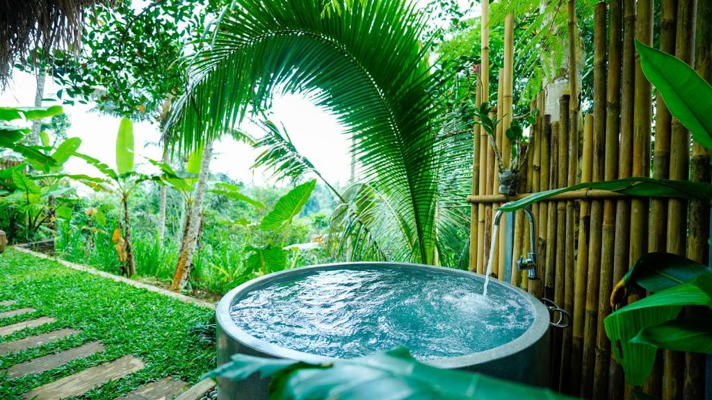 a bath tub filled with water next to a fence at D'Penglipuran Jungle House in Susut