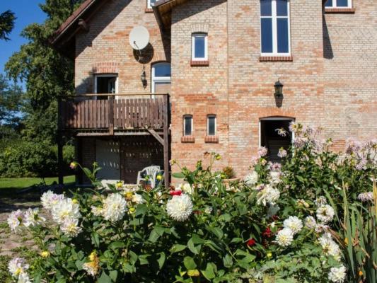 een bakstenen gebouw met een bos bloemen ervoor bij Großbauernhaus in Bentwisch