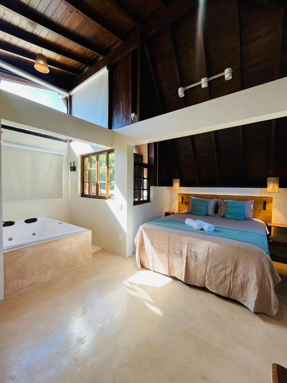 a bedroom with a bed and a tub in it at Studio Na Natureza Com Hidro - Baoba Suites in Bombinhas
