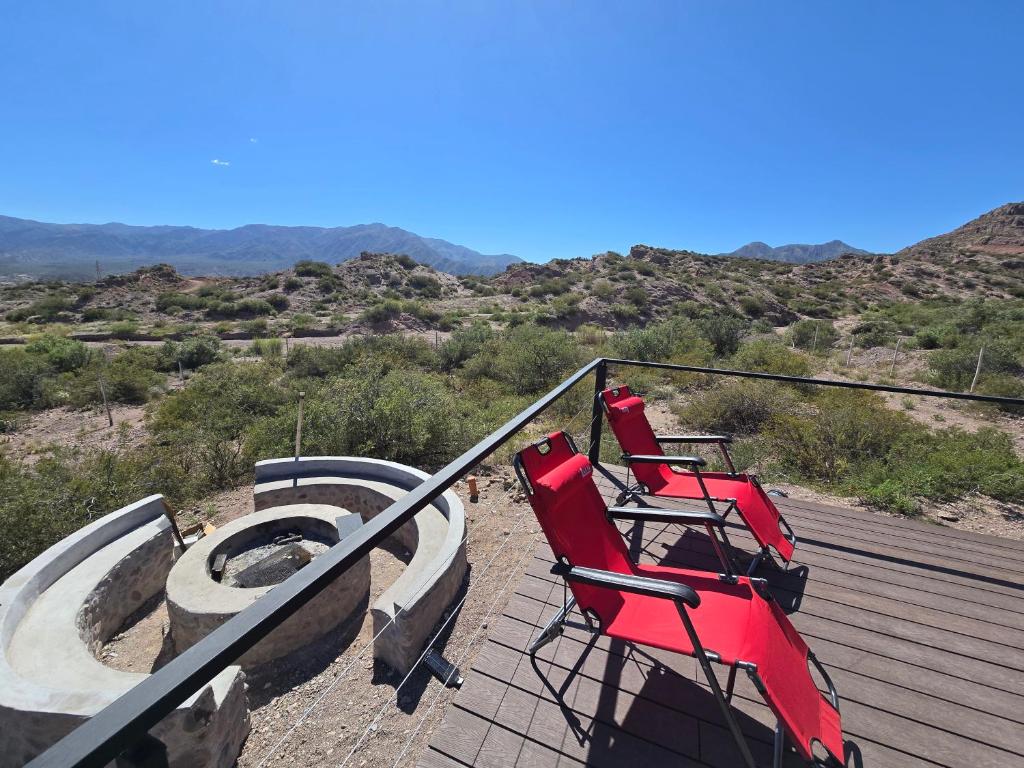 due sedie rosse su un ponte con vista sul deserto di Altos Dique Potrerillos a Potrerillos