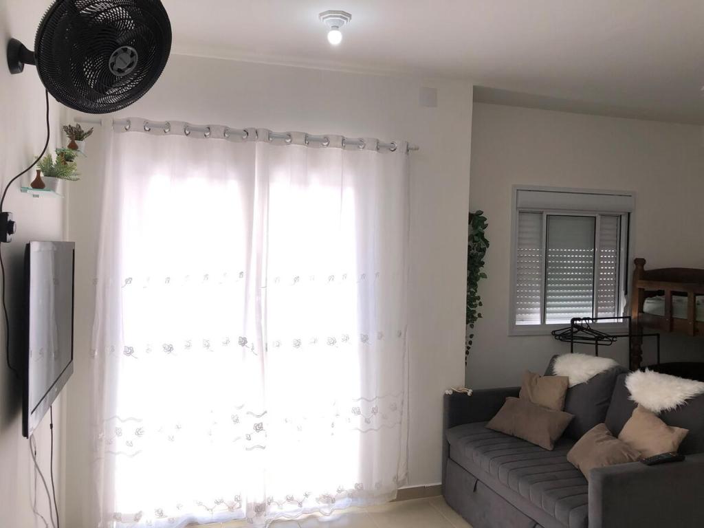 een woonkamer met een bank en een groot raam bij Beachfront apartment with swimming pool in Mongaguá