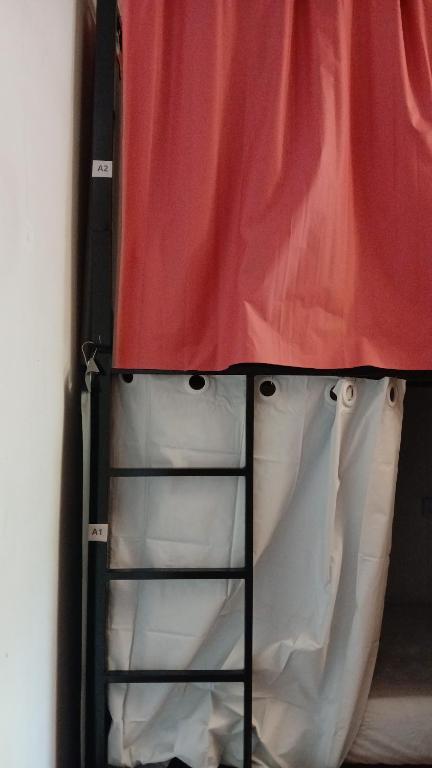 een ladder naast een rood-wit gordijn bij Sakura Hostel in Poços de Caldas