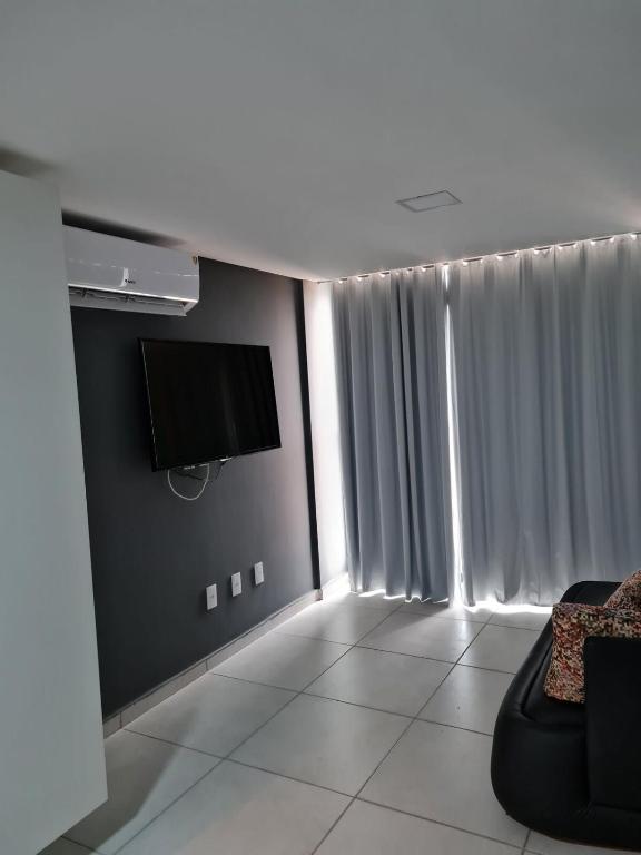 een woonkamer met een flatscreen-tv en een bank bij Conforto e sofisticação em Ponta de Campina in Cabedelo