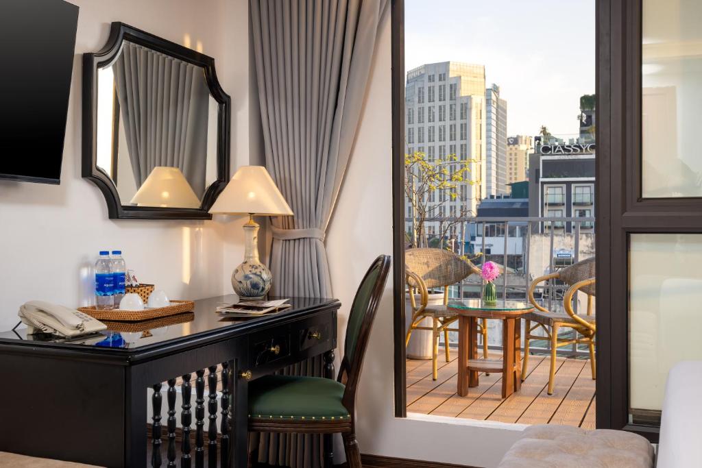 een kamer met een bureau en uitzicht op een balkon bij Golden Legend Palace Hotel & Travel in Hanoi