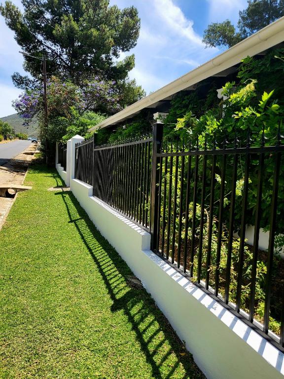 a fence with a shadow on the side of a house at Villa Olivia in Riebeek-Kasteel