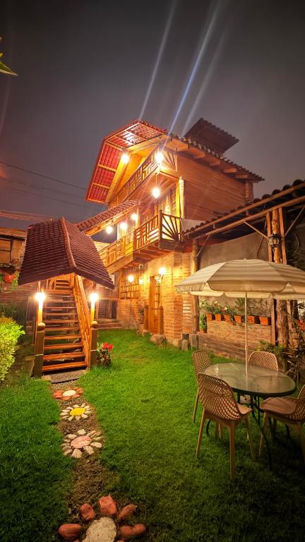 a house with a table and chairs and an umbrella at Cabaña Real con Yacuzzi rodeada de pavos reales in Ibarra