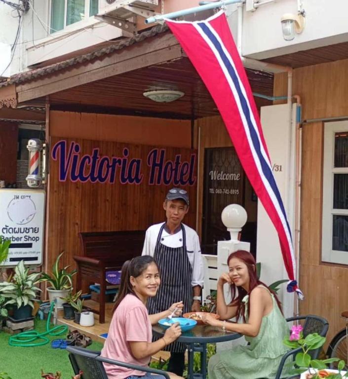 a group of people sitting at a table in front of a hotel at Victoria Hotel in Hua Hin