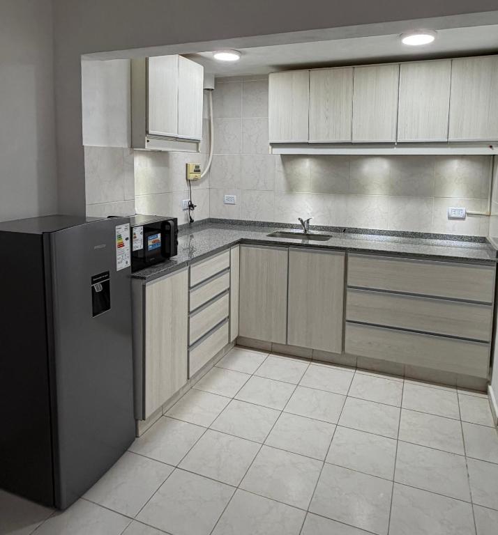 a kitchen with a refrigerator and a sink at Departamento PA in Villa Carlos Paz