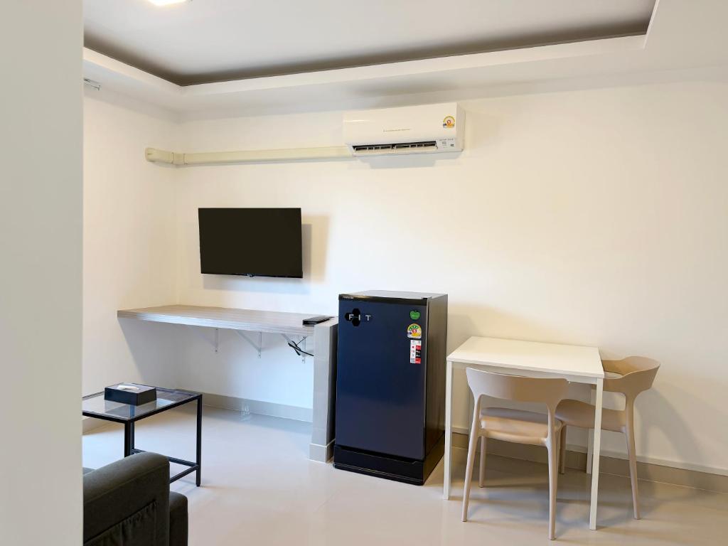 A wall-mounted television sits above a long work surface beside a compact dining area.